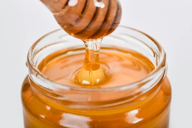 Jar of Manuka Honey on a clean minimal kitchen counter with a wooden honey dipper