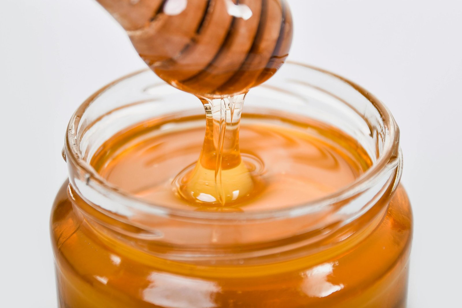 Jar of Manuka Honey on a clean minimal kitchen counter with a wooden honey dipper