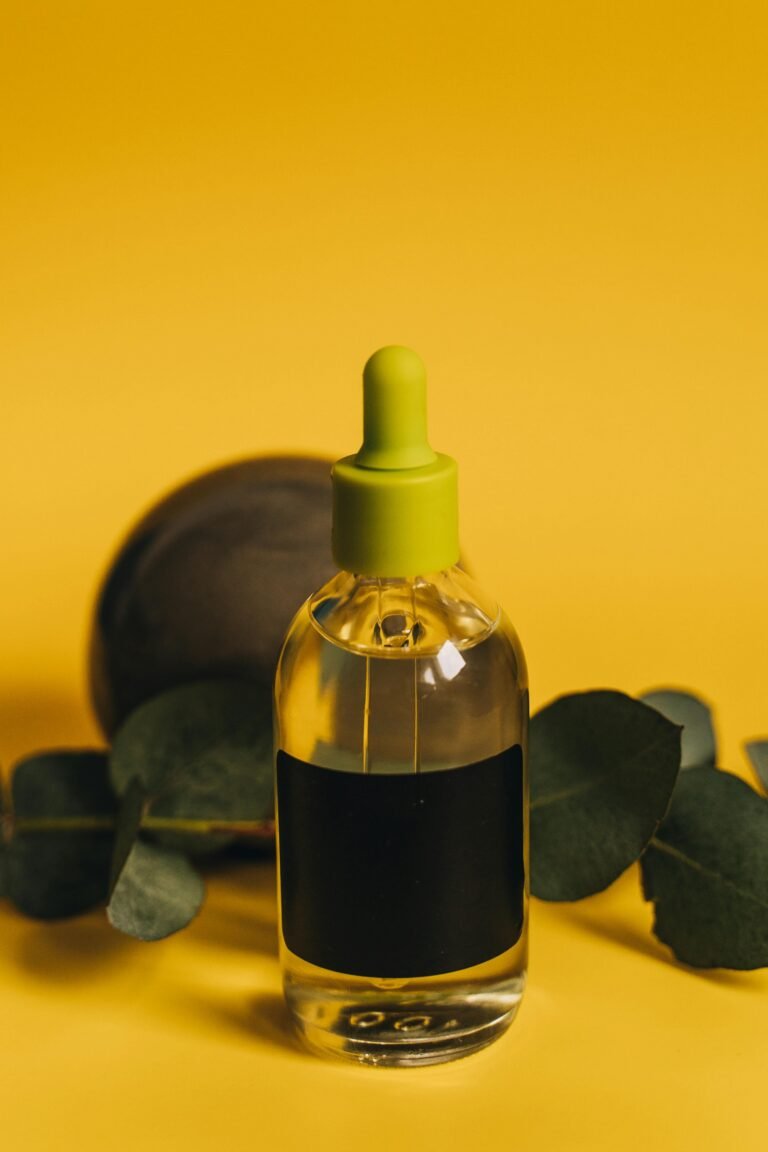 Transparent bottle with oil and dropper, yellow back ground