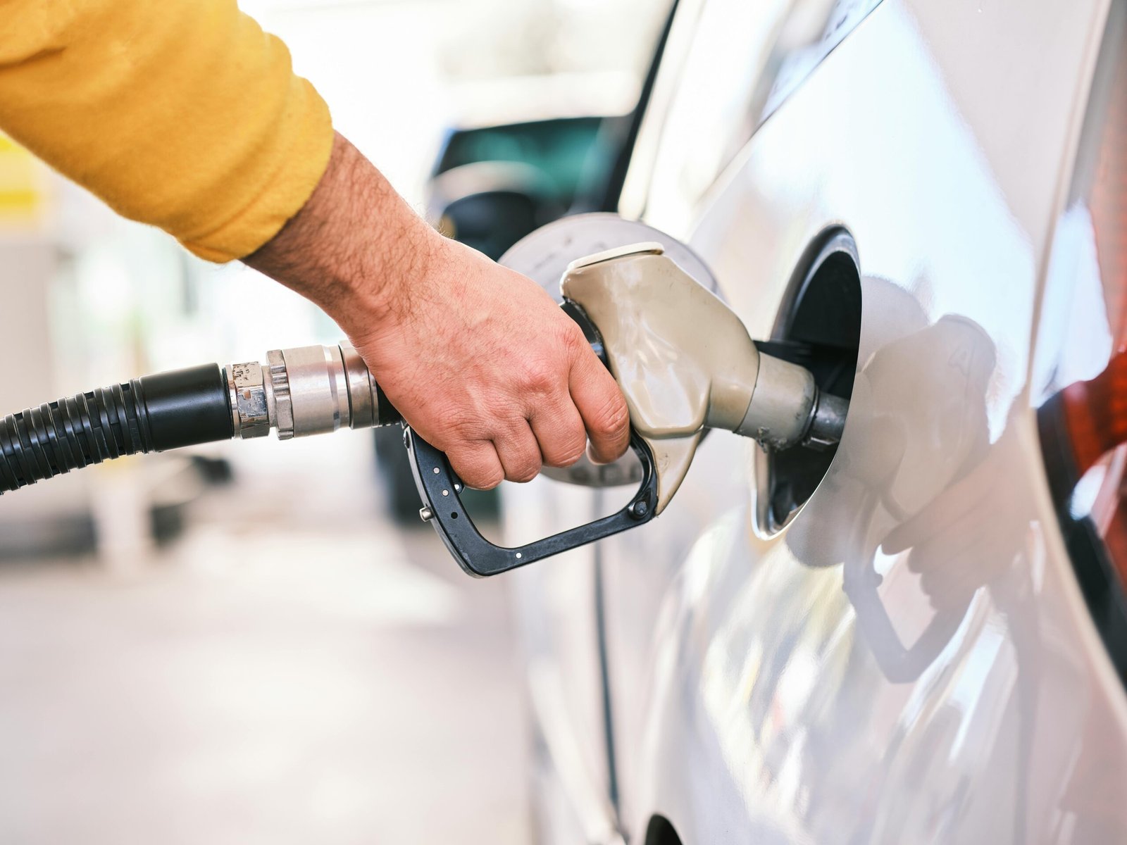 Person filling up gas in a car, only hand is showing with the gas pipe