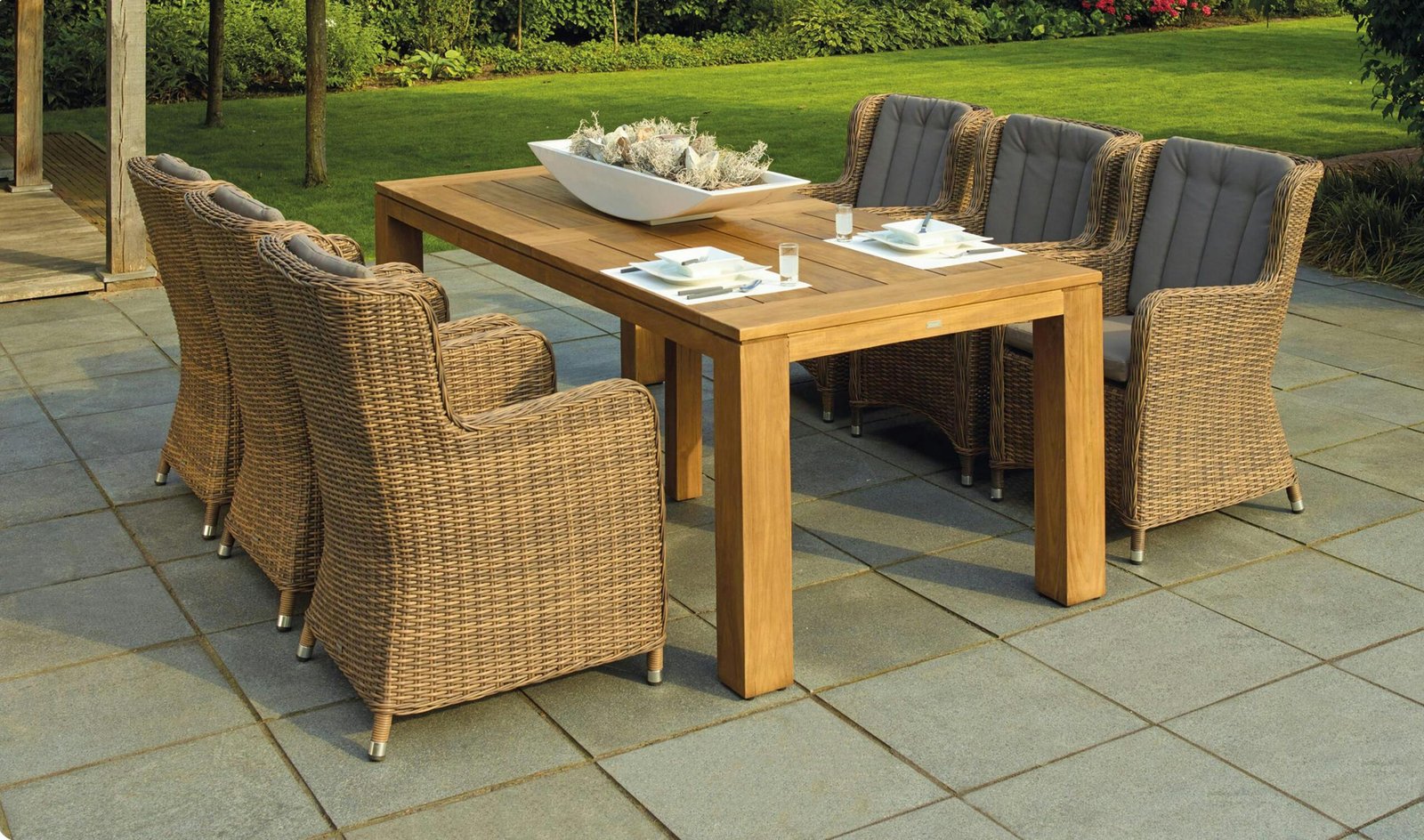 Outdoor patio dining area featuring a wooden table set with white plates and glasses