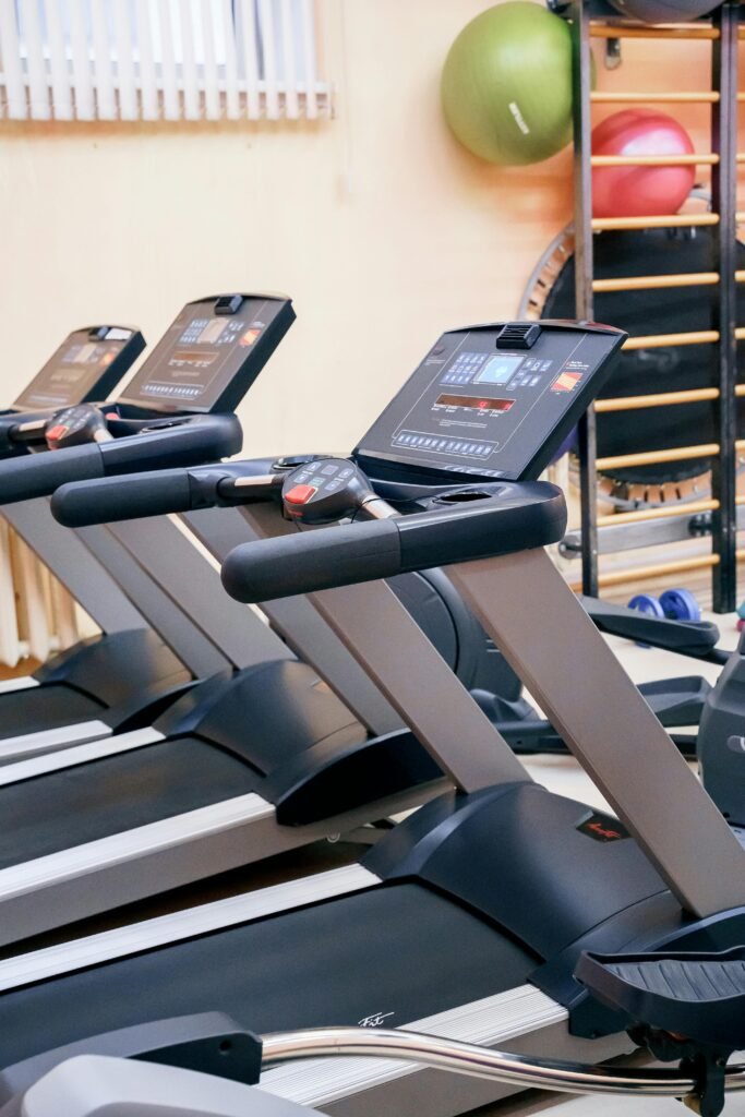 A row of treadmills in a clean gym setting, showing the treadmill benefits of daily walking for muscle tone, body conditioning, and overall wellness.