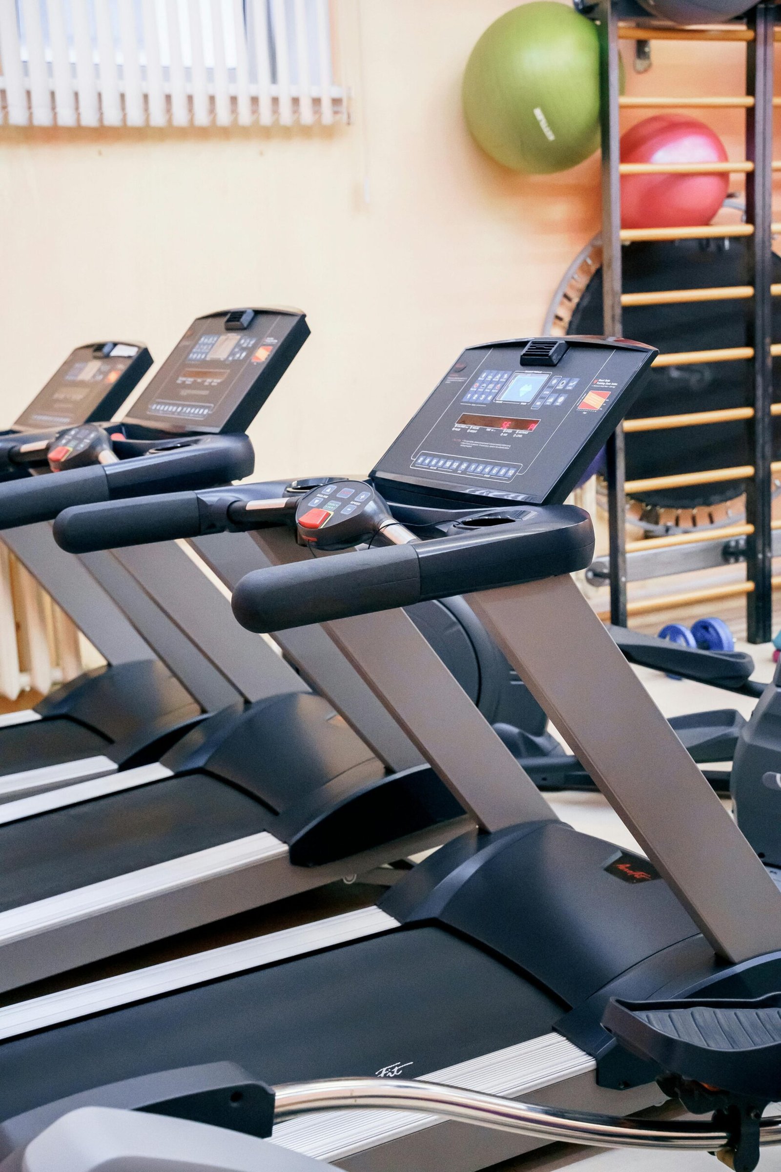 A row of treadmills in a clean gym setting, showing the treadmill benefits of daily walking for muscle tone, body conditioning, and overall wellness.