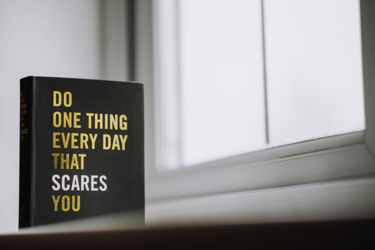 A black motivational book with bold yellow and white text placed near a bright window, creating a simple and inspiring home décor scene