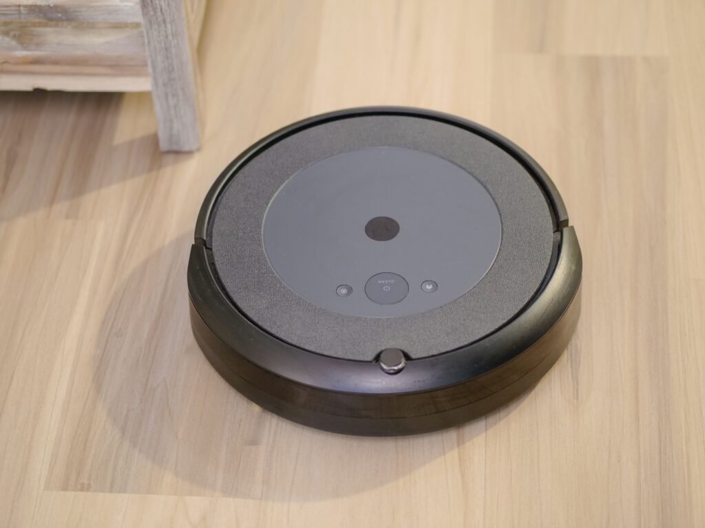 Smart home robot vacuum on a wooden floor with visible control buttons for automated cleaning.