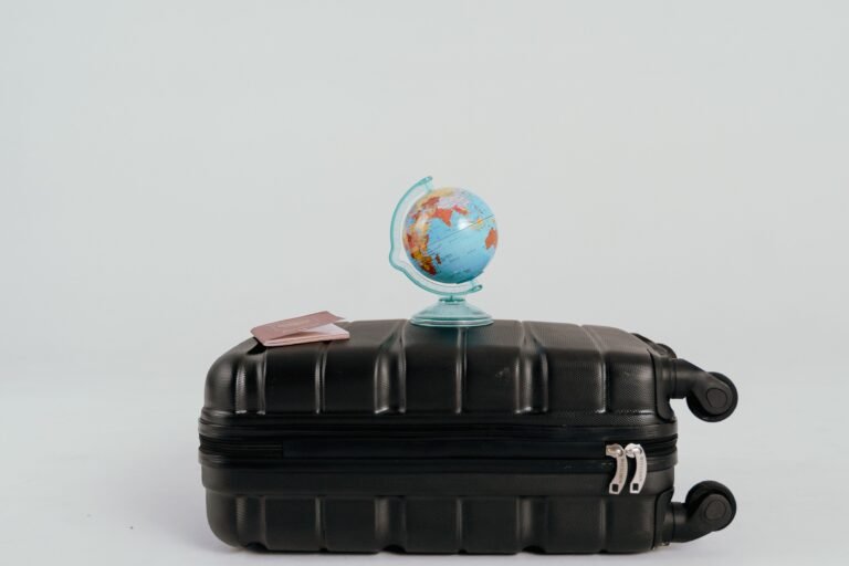 A small globe and two passports placed on a closed suitcase, symbolizing how traveling helps you heal mentally after years of working from home.