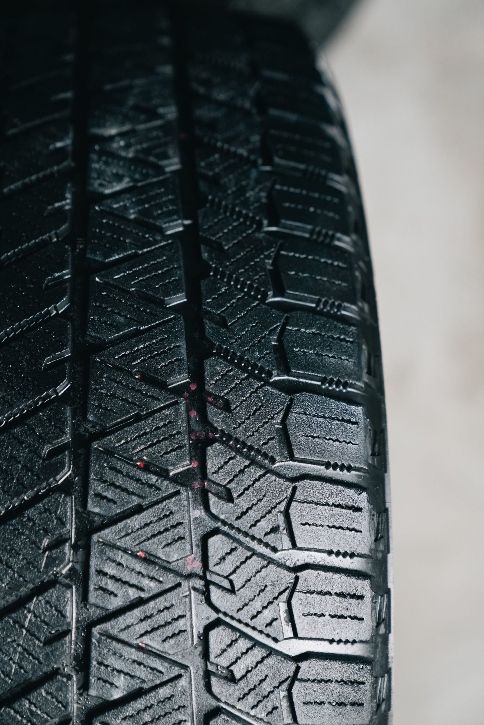 Close up of a winter tire tread showing deep grooves and many small zigzag sipes that help the tire grip snow and ice